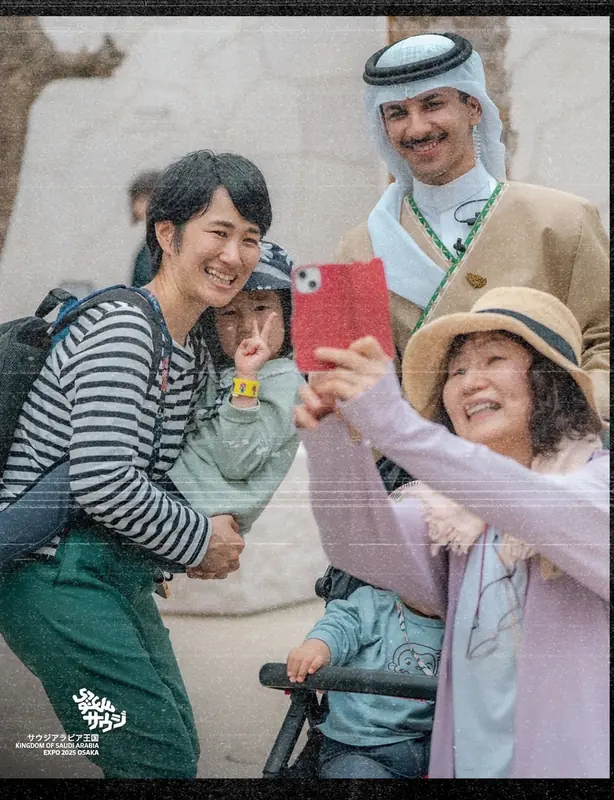 A uniformed host taking a selfie with visitors at the Saudi Pavilion