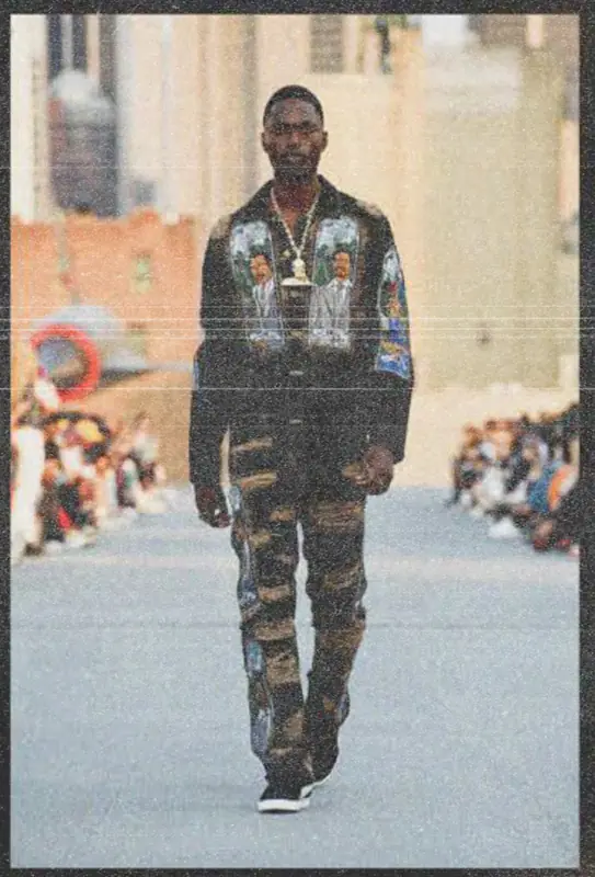 Model on the Intrepid runway in a dark embroidered jacket and trousers